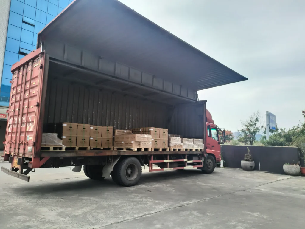 Camion rouge chargé de cartons palettisés d'actionneurs Eaton et de pièces de moteurs diesel destinés à l'exportation chez Volgen Power.